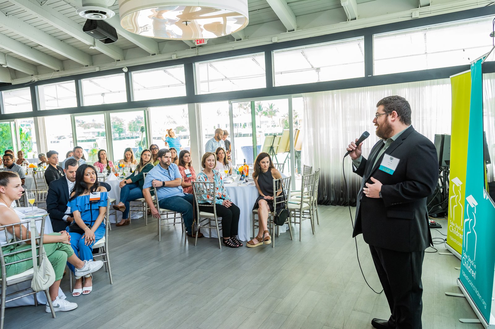 A host speaking to a seated audience at a Take Stock in Children event