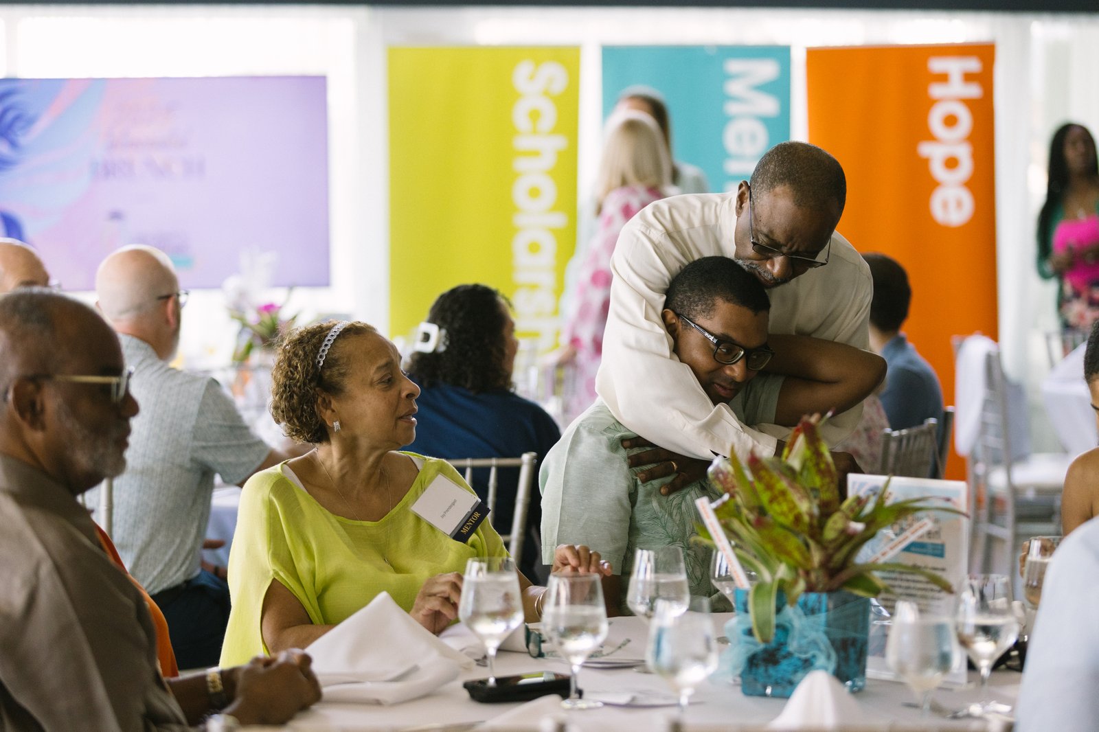 Guests seated at tables in front of the Scholarships, Mentors and Hope banners