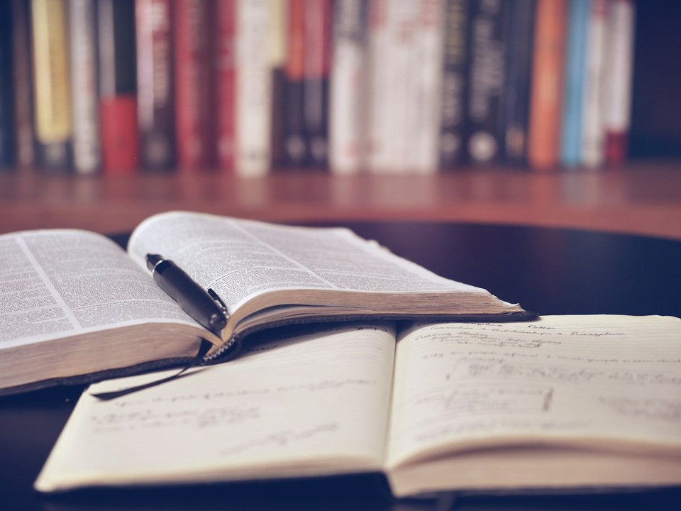 An open textbook, notes, and pen on a study desk