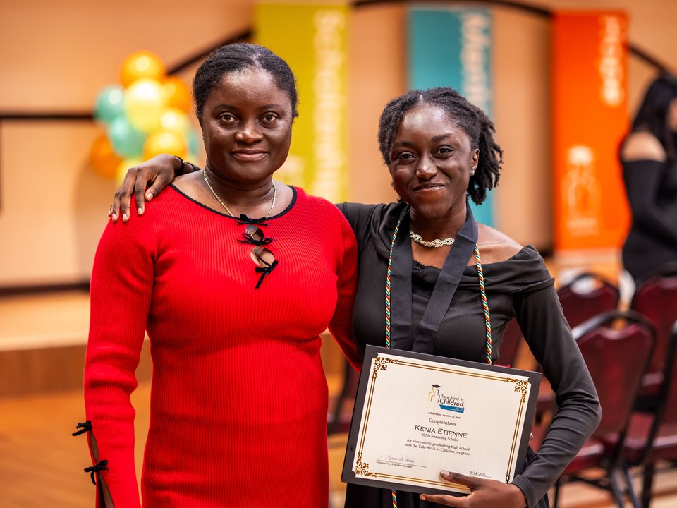 A graduating scholar proudly displaying her graduation certificate alongside her mentor